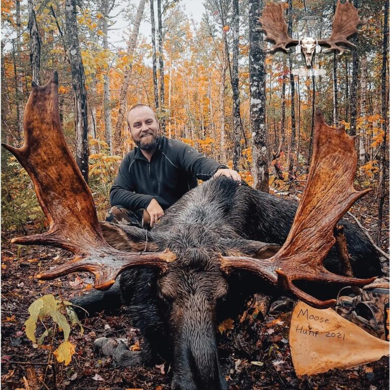 A man sitting on the ground with his moose.