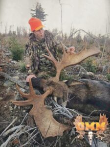 A man in camouflage jacket holding an animal.