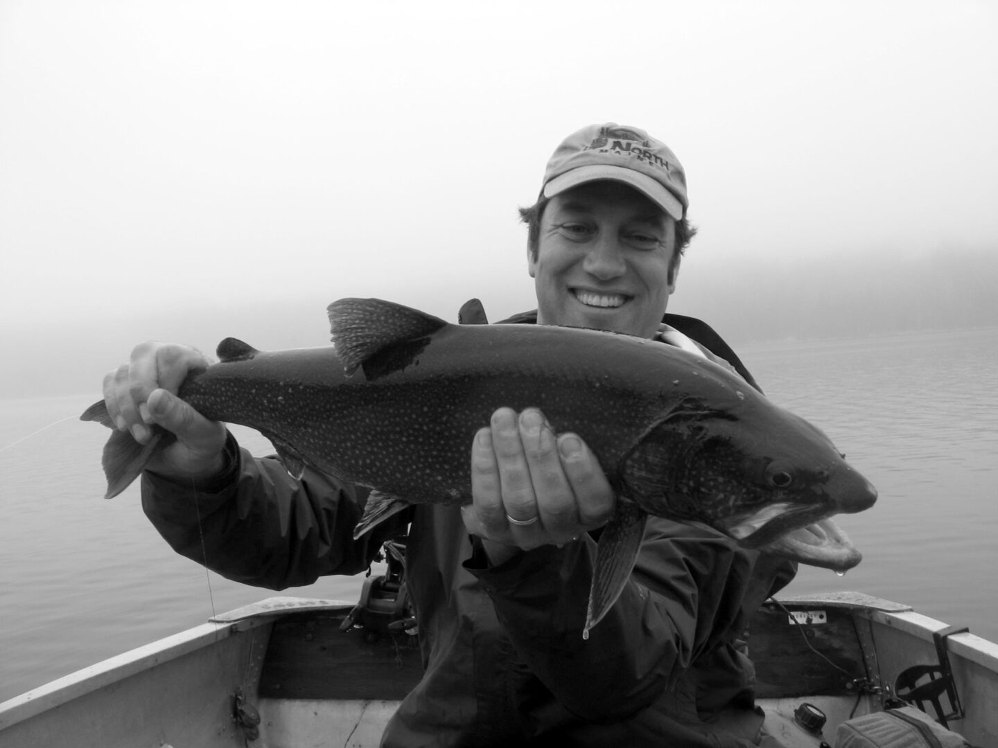 A man holding a fish in his hand while sitting on a boat.