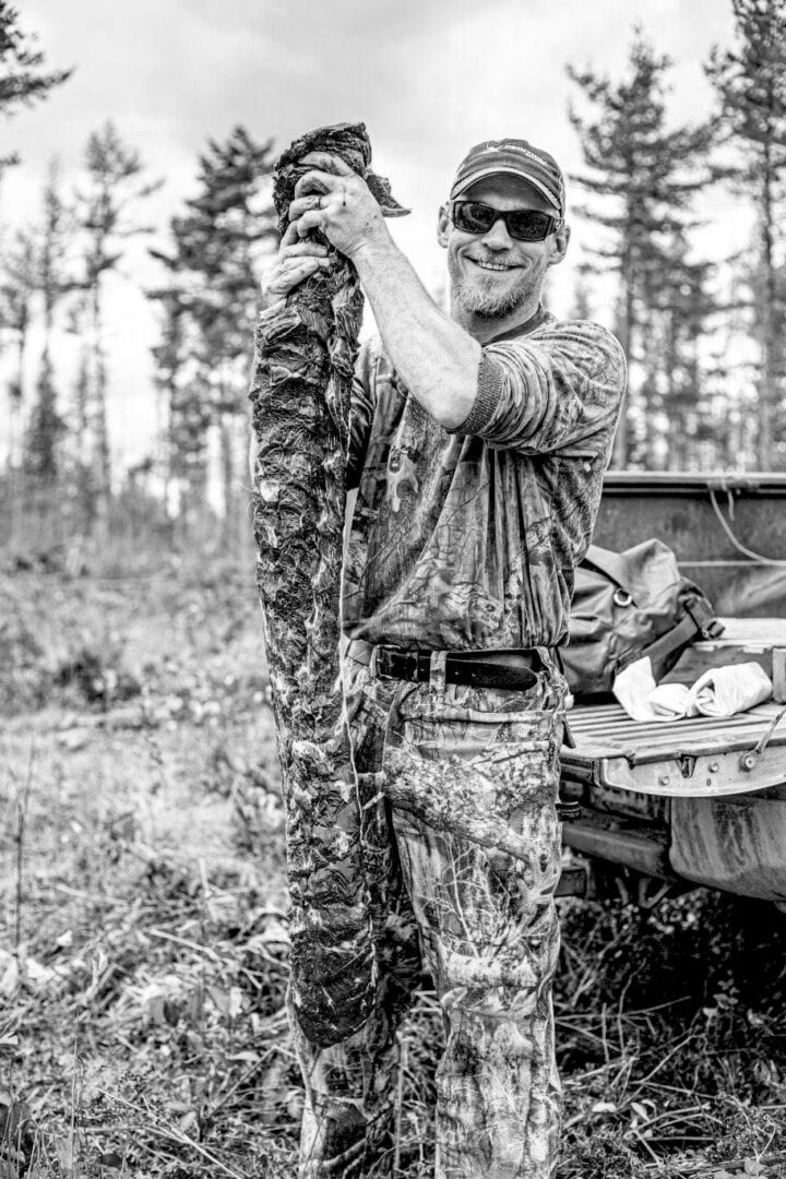 A man holding a large piece of wood in the woods.