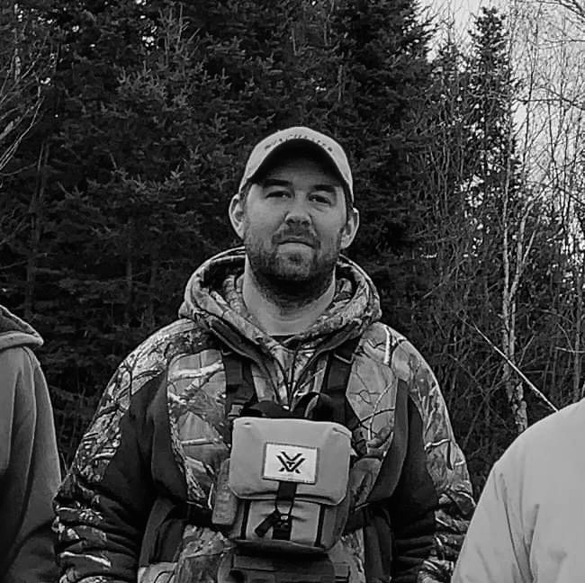 A man in camouflage jacket holding a camera.