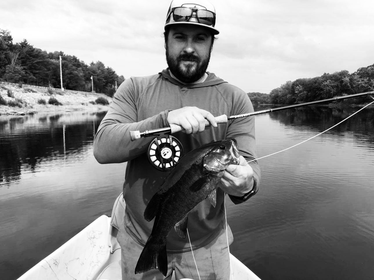 A man holding a fish while standing on top of a boat.