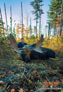 A man sitting in the woods with his moose.