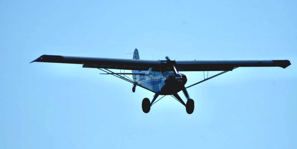 A small airplane flying in the sky with its landing gear down.