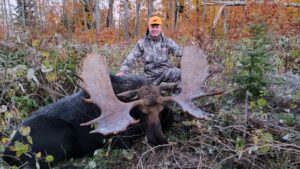 A man sitting in the grass with his moose.
