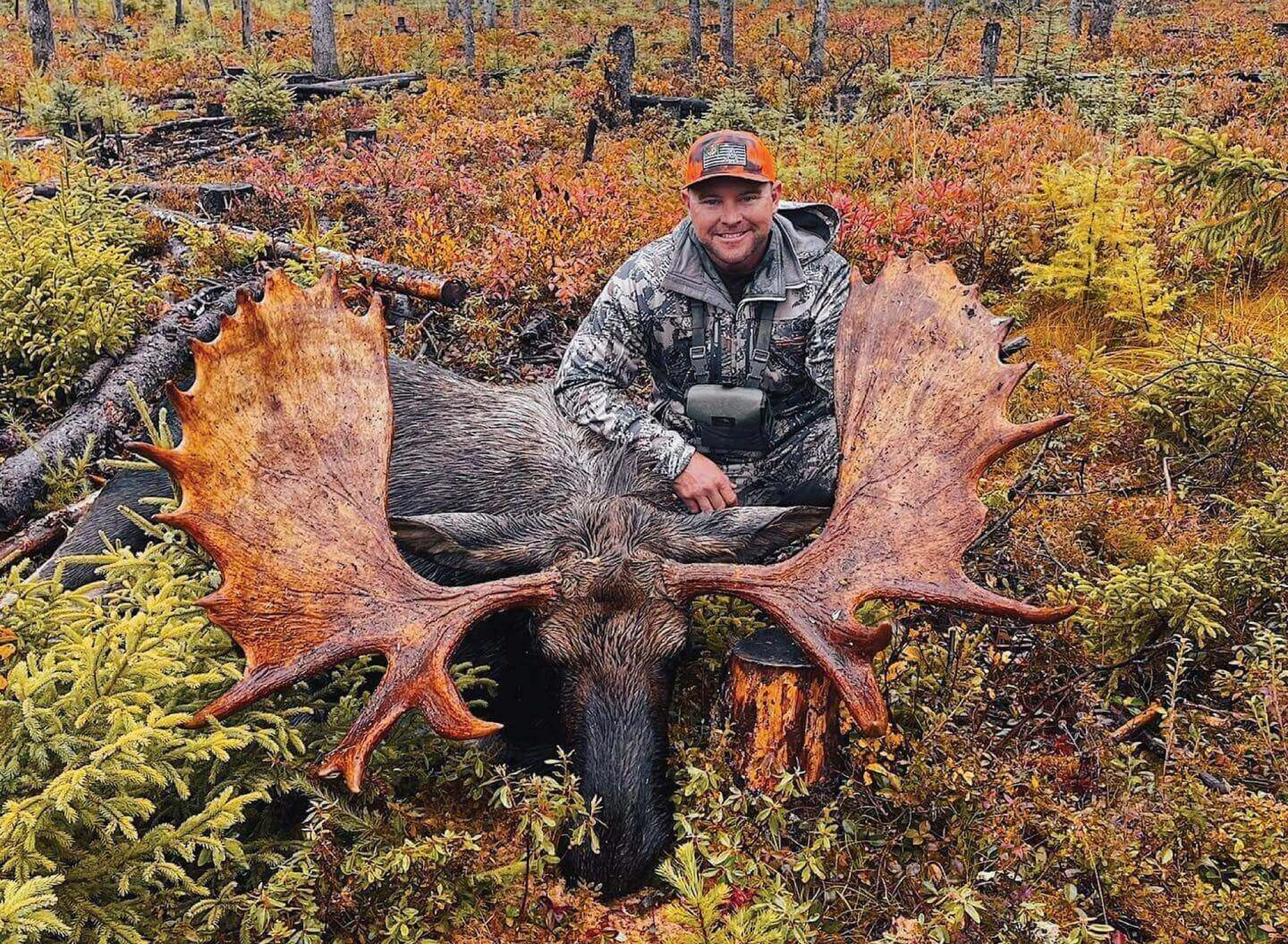 Smiling hunter posing with massive antlered moose