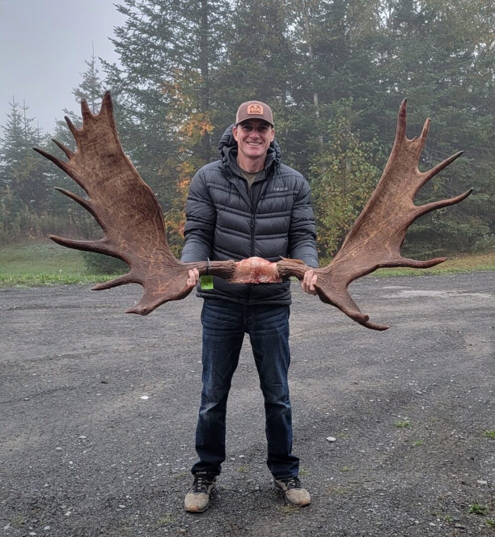 Man holding large moose antlers.