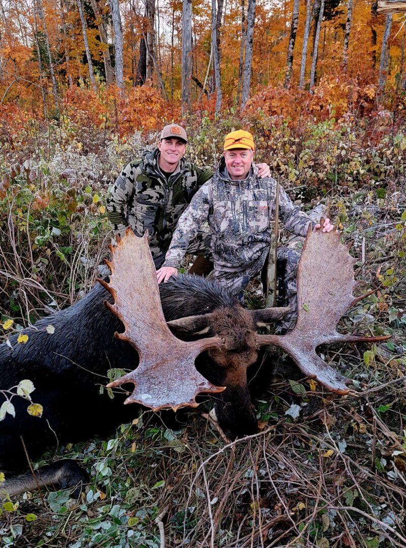 Two hunters pose with a harvested moose.