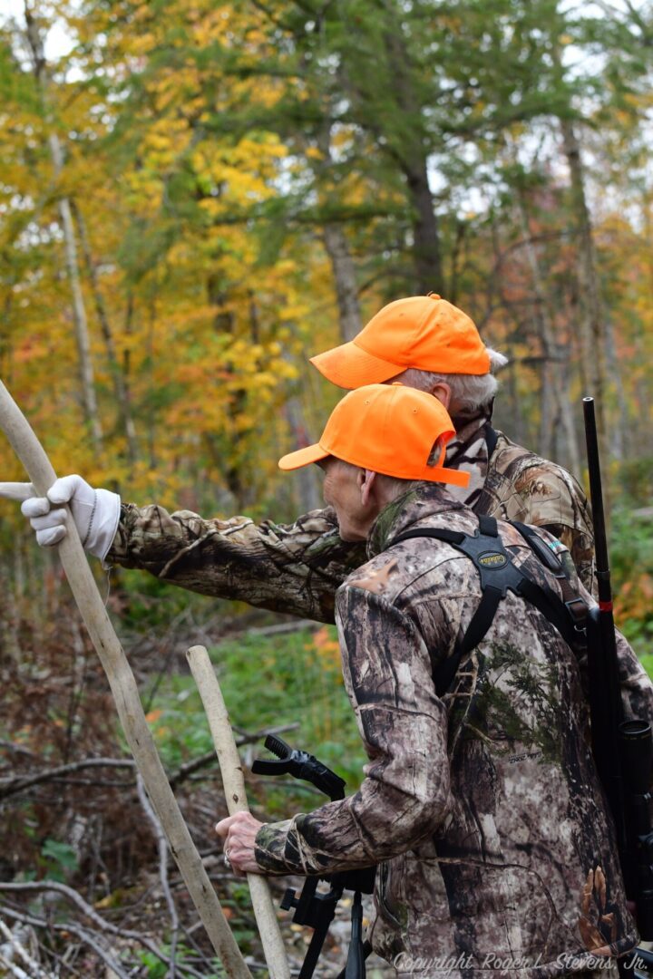 Two hunters in camo gear in the woods.