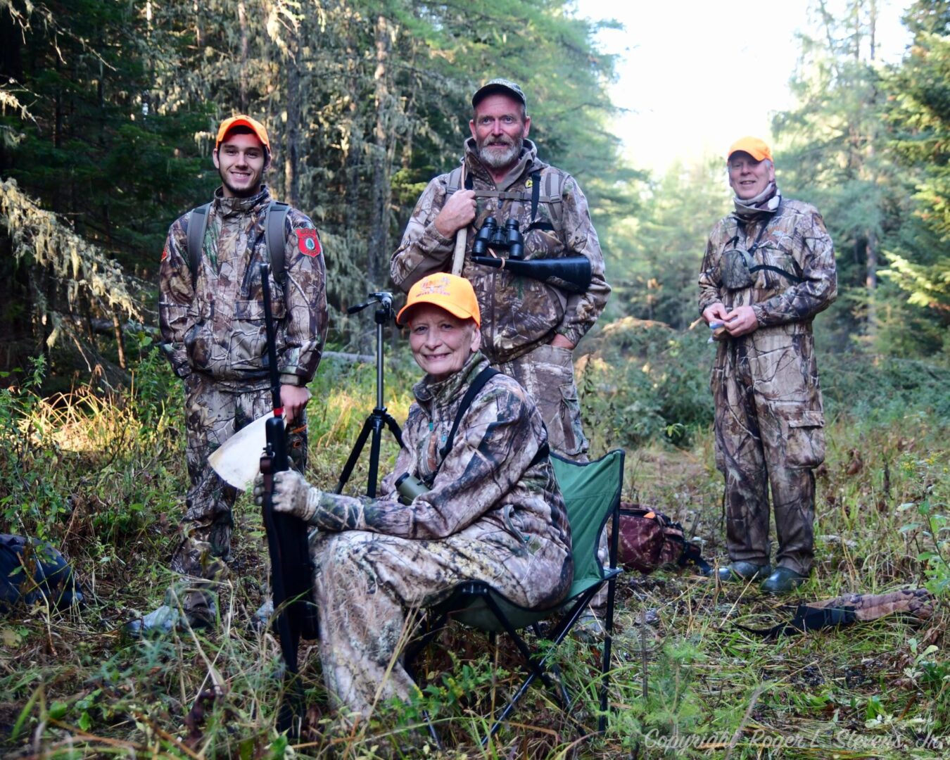 Four hunters in camouflage clothing in woods.