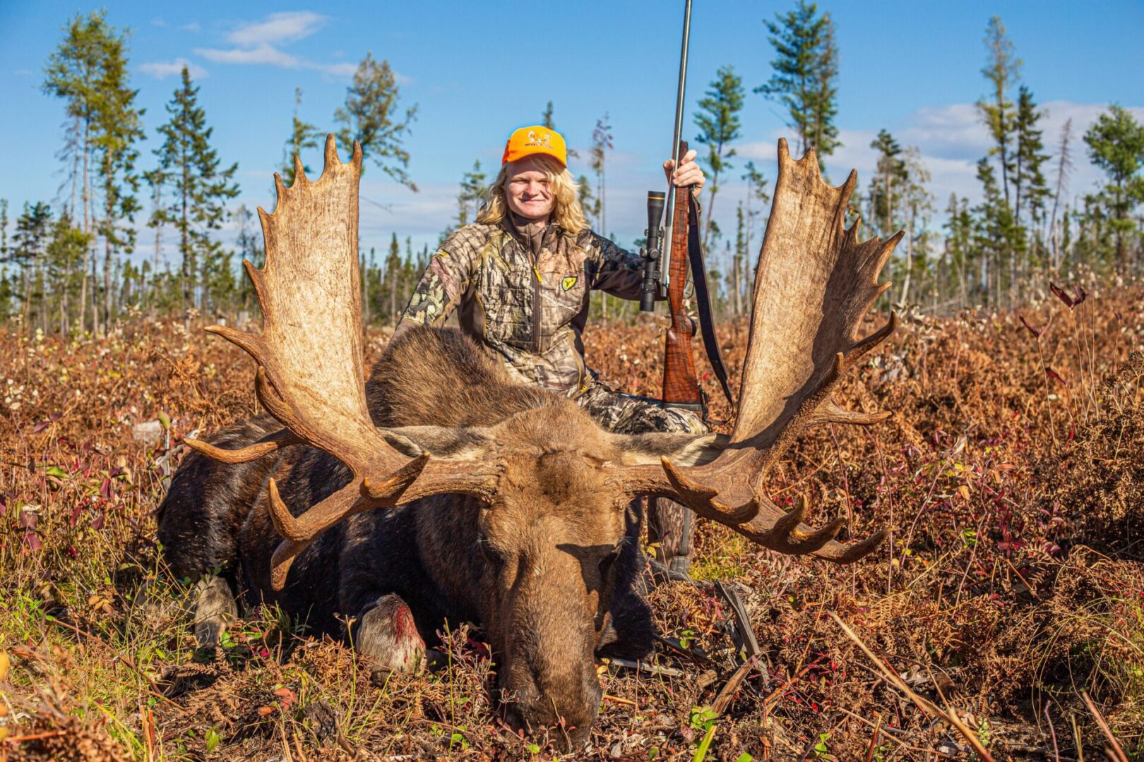 Hunter with a rifle and a harvested moose.