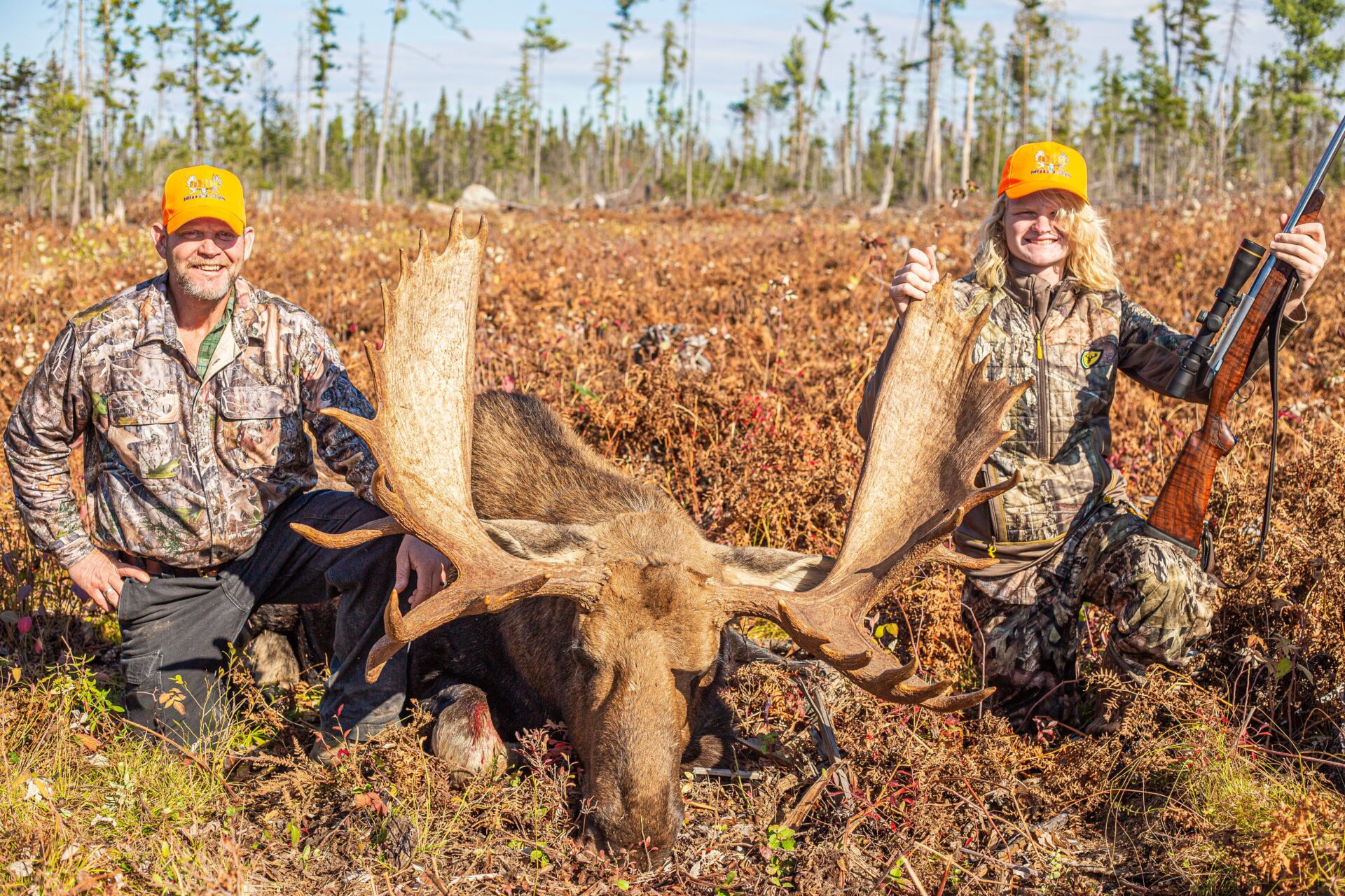 Two hunters pose with a harvested moose.