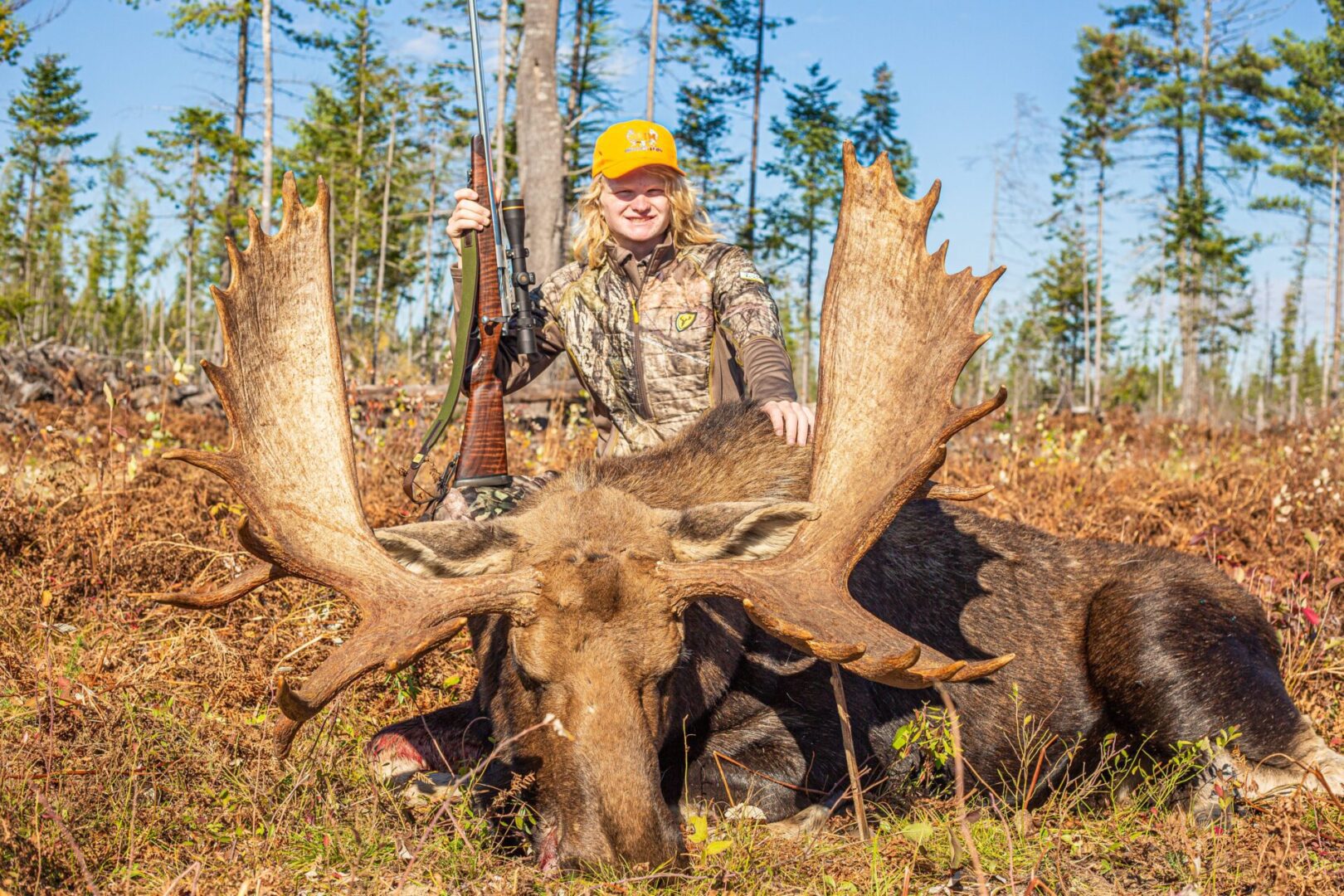 Hunter with rifle and harvested moose.