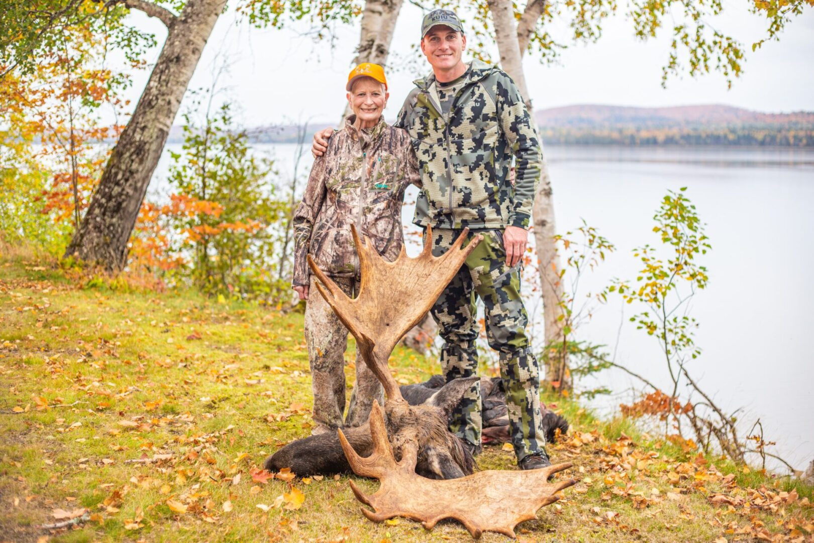 Two hunters pose with a moose antler.