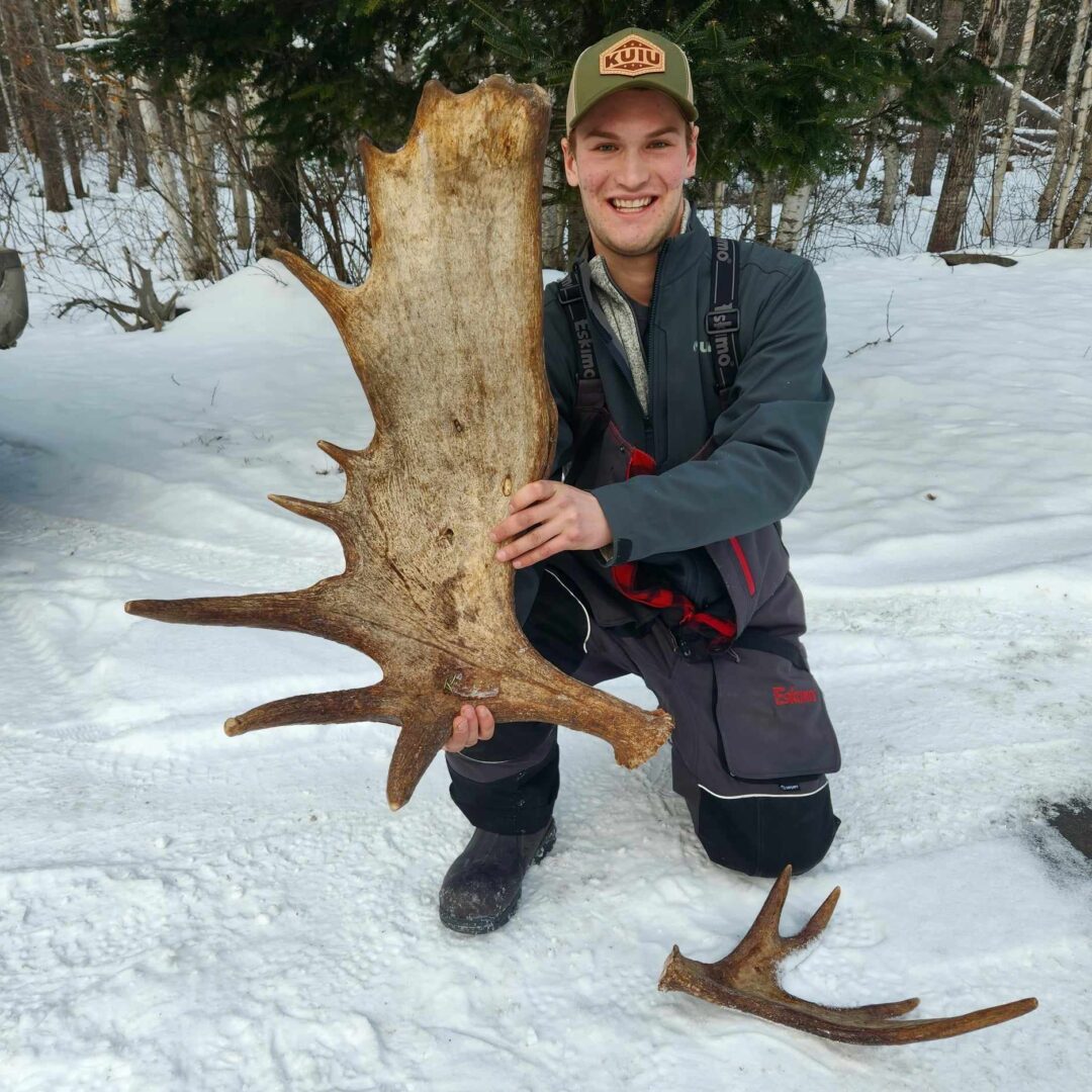 Man holding a large moose antler.